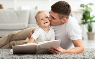 Father Laying on the Floor Kissing His son on the cheek while they read a book
