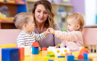 Two toddlers playing while a teacher watches