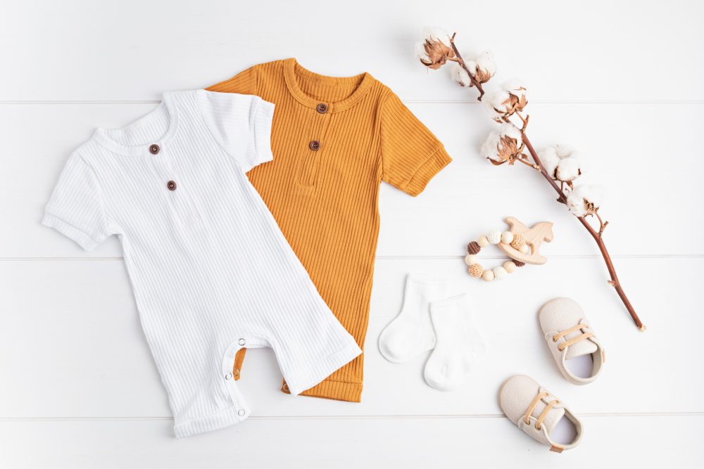 Two gender-neutral baby outfits in white and orange