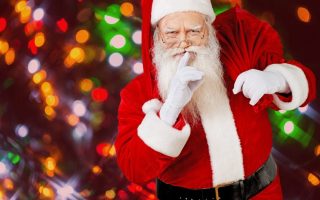 Santa with his forefinger held up to his lips.