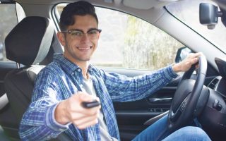Male teen driver behind the steering wheel.