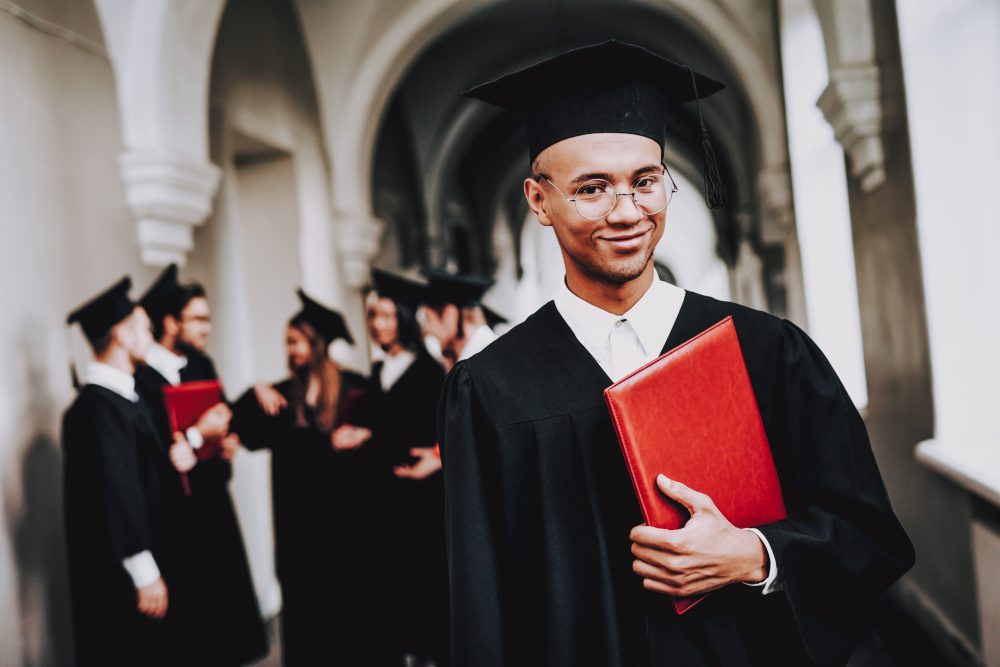 Student in a cap and gown, holding his diploma