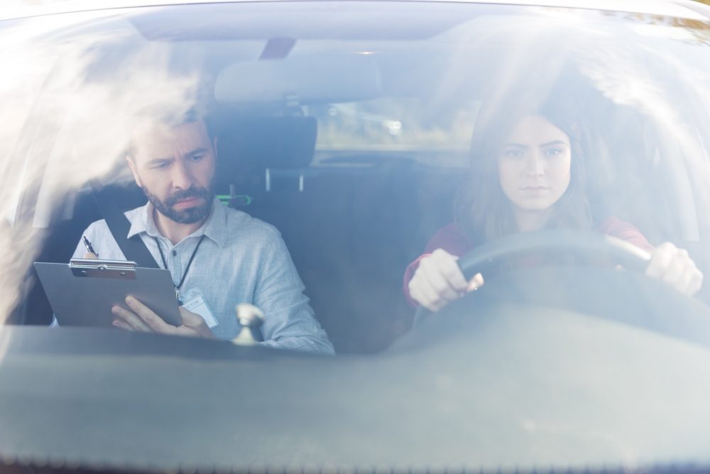 Female teen driver in a car with a driving instructor in the passenger seat