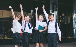 Beautiful school children active and happy on the background of school in uniform