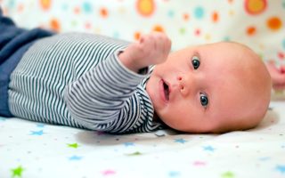 Portrait of a cute newborn baby who lies on his back in a crib