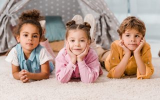 beautiful multiethnic children lying on carpet and looking at camera