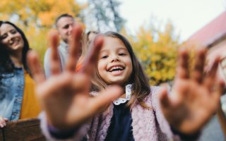 A portrait of happy young family with two small children in autumn nature, having fun.