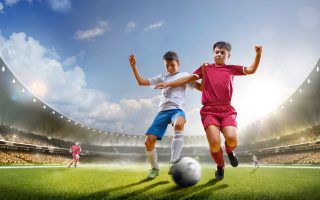 Childrens are playing soccer on grand arena in sunlights