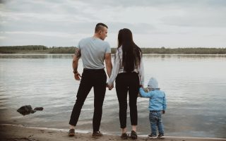 Young white family with their son on the beach on the sand in the summer by the river