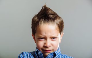 Closeup portrait of cute young boy gesturing anger