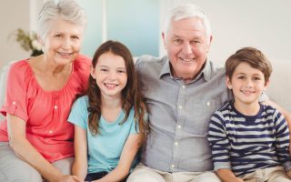 Portrait of grandparents and grandchildren sitting together on sofa in living room