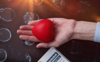 Red heart in the palm of your hand against the background of a medical card.