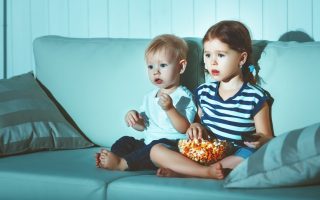 Children brother and sister watching TV in the evening