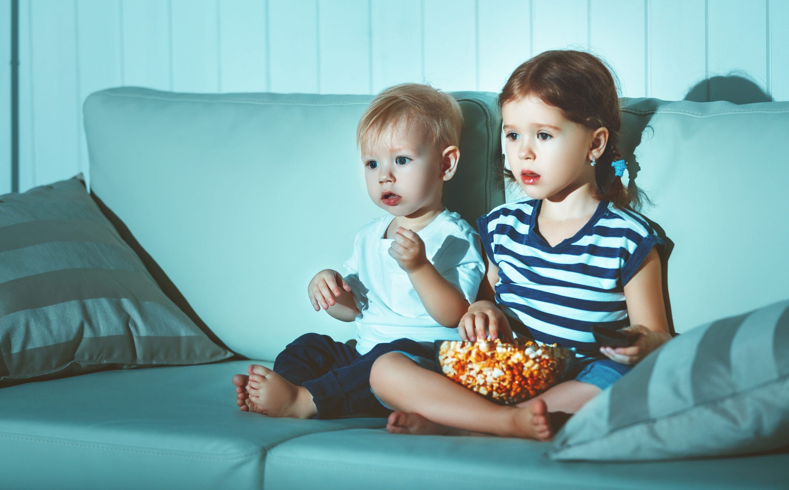 Children brother and sister watching TV in the evening
