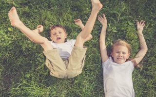 Two happy children playing on the grass at the day time. Concept Brother And Sister Together Forever
