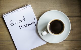 Cup of black coffee and good morning note on the table