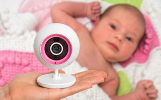 Hand of mother is holding baby monitor camera for safety of her cute baby