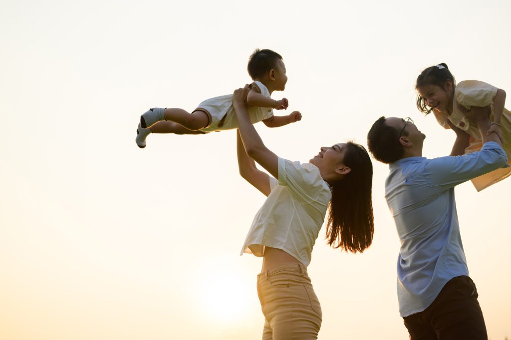 Happy father and mother holding children playing together in park with sunset view, Cheerful family father mother and children enjoying picnic at park, Family with healthy lifestyle, Life insurance