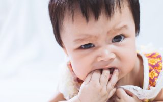 Portrait of cute asian baby girl sucking her fingers in her mouth on white background