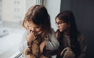 Child surrounded by toys, looking uninterested