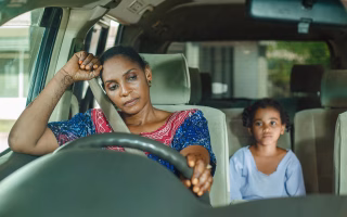 Parent driving a car while a child in the backseat unbuckles their seatbelt