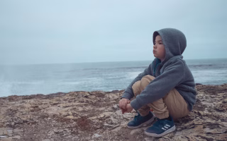 Child sitting alone, looking emotionally overwhelmed