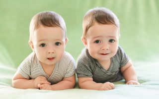 Newborn twins boys are lying on the bed