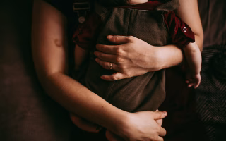 Adult hugging child with a distant expression