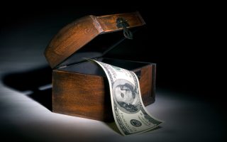 Hundred dollars and wooden chest. A black background. Beautiful illumination.