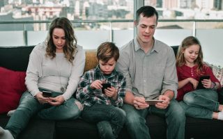 Young smiling cheerful family playing with their smartphones together at home