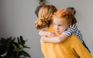 beautiful young mother and cute daughter embracing at home