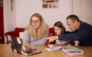 A smiling child proudly holding up a report card with high grades while a parent hands over money, symbolizing the reward system and raising questions about the impact of paying kids for academic performance.