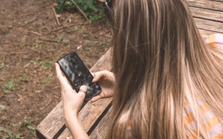 Teen using phone while parent looks on.