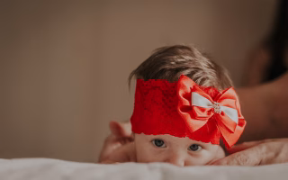 Baby in a red bow, exploring unique name regrets