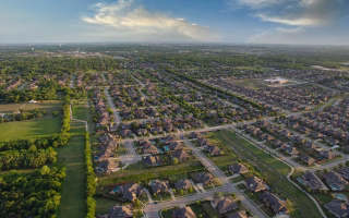 a quiet suburban neighborhood, looking contemplative or uncertain, with rows of similar houses and empty sidewalks