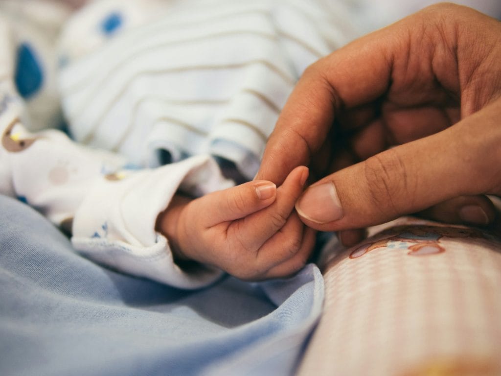 parent holding baby's hand