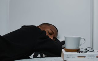 man sleeping next to a cup of coffee