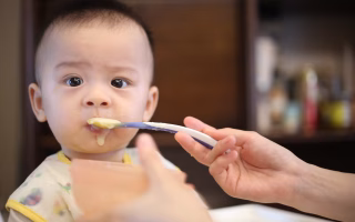 Baby being spoon-fed soft food.
