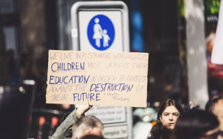Protester holding a sign about children sacrificing education to fight for their future.