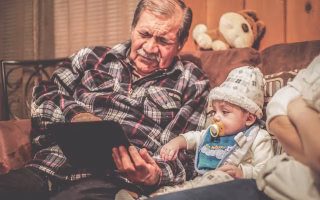Child holding tablet with his grandfather