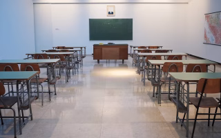 Empty classroom with rows of desks facing a chalkboard.