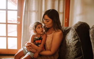 Mother and daughter talking on a couch at home