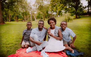 Smiling family sitting together on a picnic blanket in a park