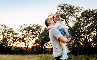 Father lifting his daughter outdoors, suggesting a happier outcome after divorce.