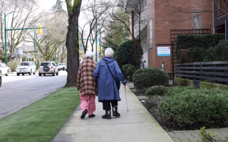 Two elderly women walking together on a city sidewalk