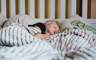 Young child sleeping peacefully in bed under a soft blanket.