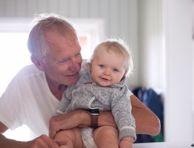 Smiling grandfather holding a happy baby indoors.