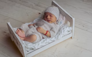 Sleeping newborn in a tiny wooden bed, symbolizing family naming decisions.