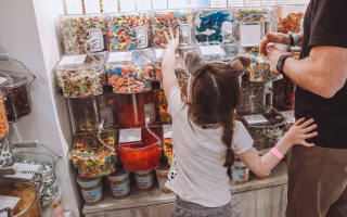 Young girl reaching for candy in a self-serve candy store.