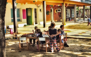 Children painting and playing outdoors at a colorful preschool.
